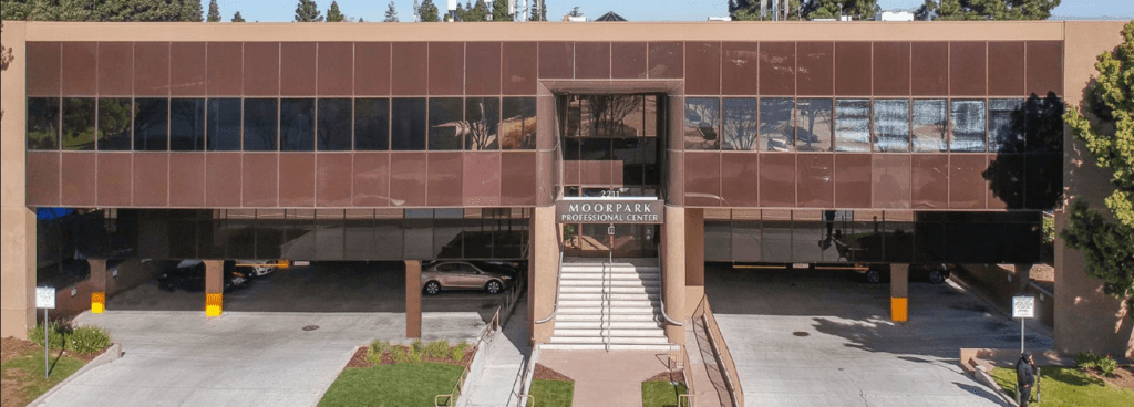 Exterior of Moorpark Professional Center, a two-story office building housing the Sunnyvale Implant Center, with front entrance and parking below.