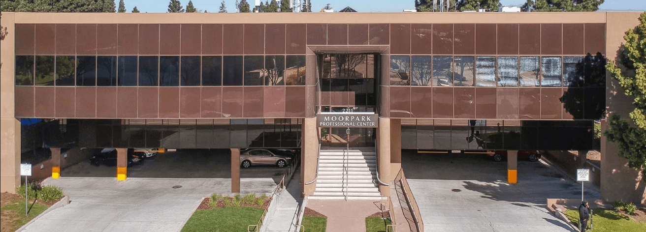 Exterior of Moorpark Professional Center, a two-story office building housing the Sunnyvale Implant Center, with front entrance and parking below.
