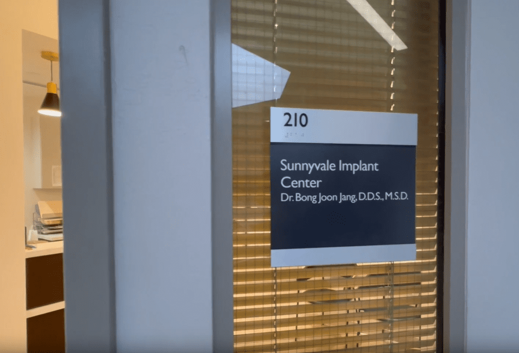 Office door signage for Sunnyvale Implant Center, Suite 210, led by Dr. Bong Joon Jang, D.D.S., M.S.D., specializing in dental implants.