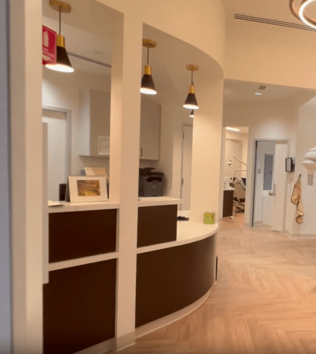 Sleek and inviting front reception desk at Sunnyvale Implant Center with pendant lighting, combining comfort and professionalism