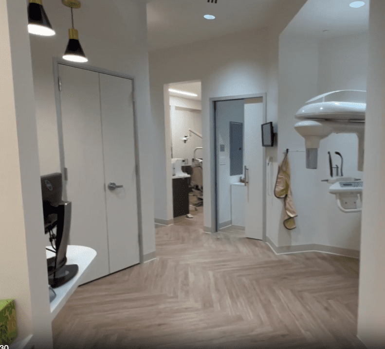 Central hallway at Sunnyvale Implant Center with view into dental operatory and panoramic X-ray machine, reflecting a state-of-the-art dental facility.